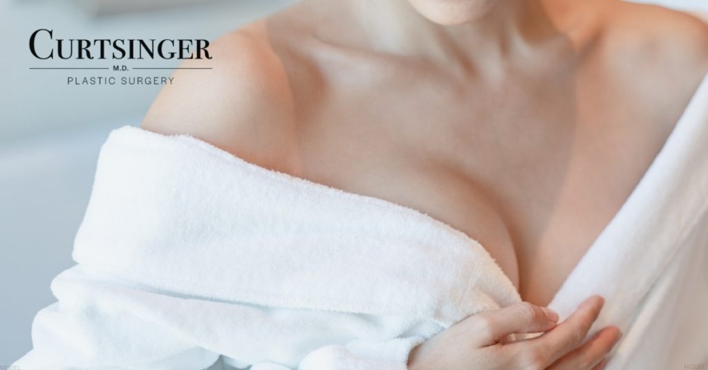 Woman in white robe with her hands on her chest (model) Dr. Luke Curtsinger Logo